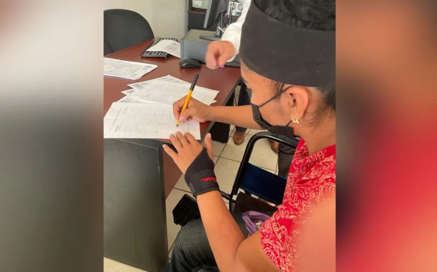 Artesana zapoteca firmando documentos