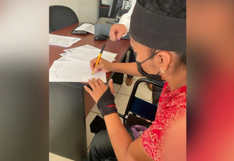 Artesana zapoteca firmando documentos